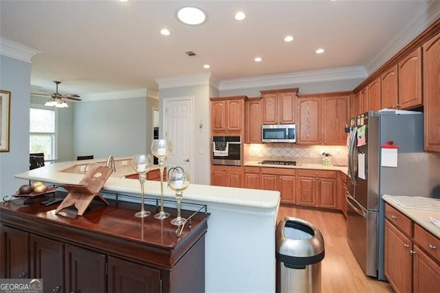 kitchen with crown molding, light hardwood / wood-style flooring, decorative backsplash, and stainless steel appliances