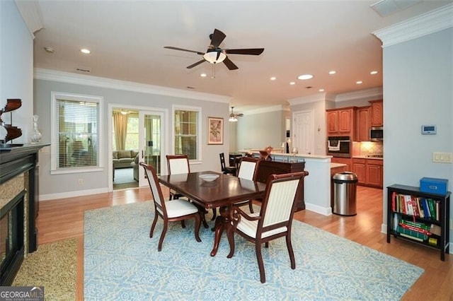 dining area with crown molding, light hardwood / wood-style flooring, a fireplace, and ceiling fan