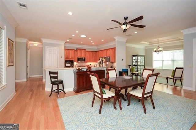 dining room featuring light hardwood / wood-style floors, crown molding, and ceiling fan with notable chandelier