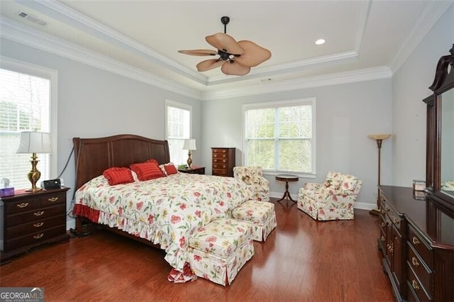 bedroom with dark wood-type flooring, ceiling fan, ornamental molding, and a tray ceiling