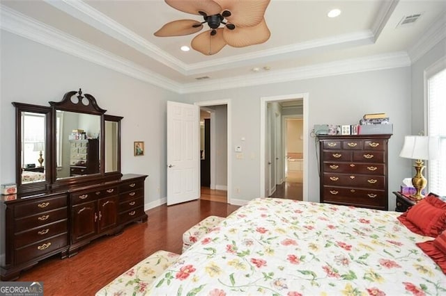 bedroom with crown molding, dark hardwood / wood-style floors, a tray ceiling, and ceiling fan