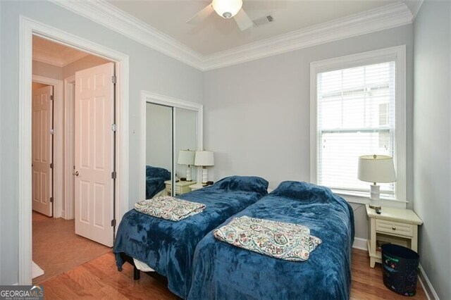 bedroom featuring a closet, ceiling fan, crown molding, and multiple windows