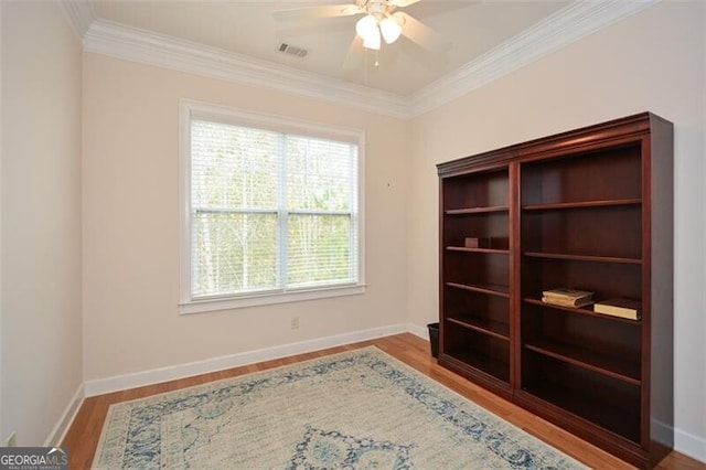 spare room with a wealth of natural light, ornamental molding, light hardwood / wood-style flooring, and ceiling fan