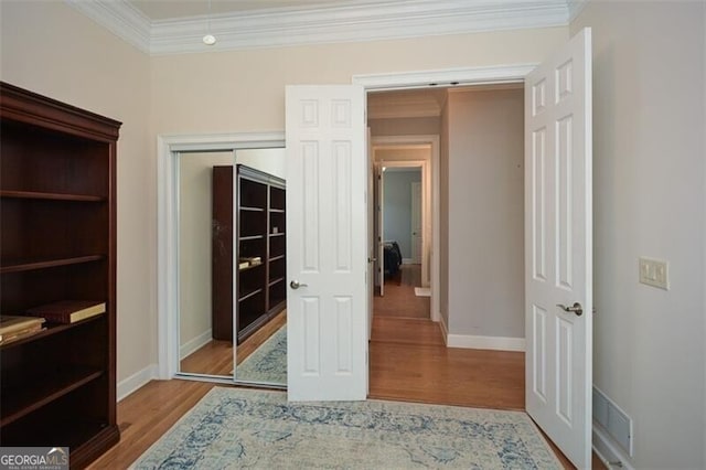 interior space featuring a closet, light hardwood / wood-style floors, and ornamental molding