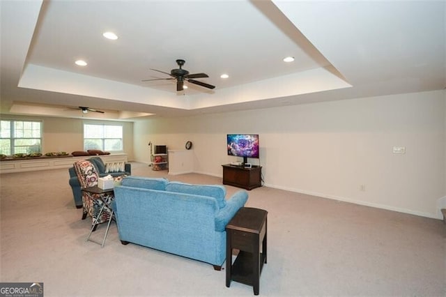 carpeted living room featuring ceiling fan and a raised ceiling