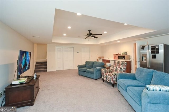 living room with ceiling fan, carpet flooring, and a tray ceiling