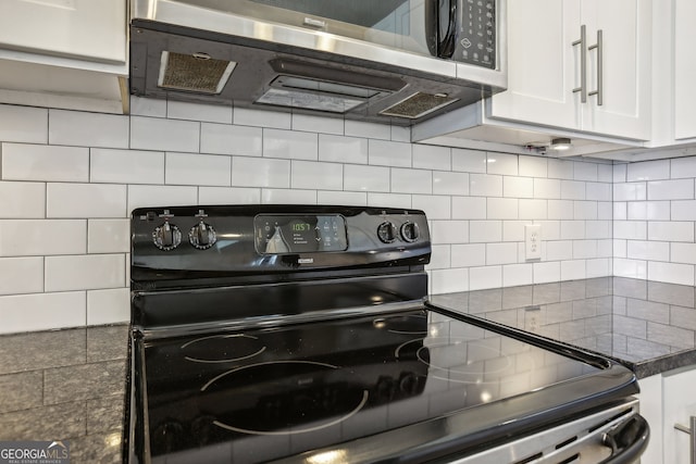 kitchen featuring black electric range, tasteful backsplash, white cabinetry, and dark stone countertops