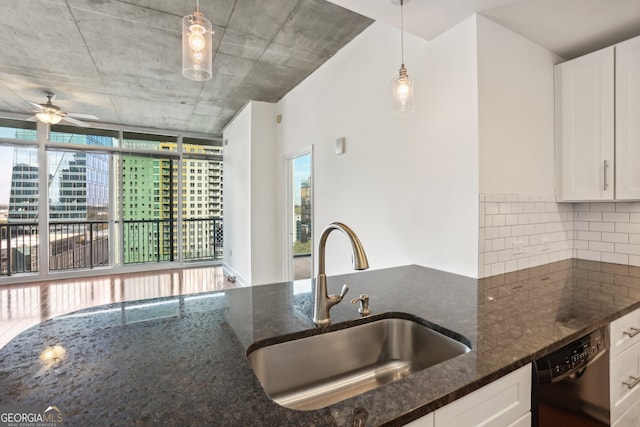 kitchen featuring white cabinets, sink, tasteful backsplash, decorative light fixtures, and dark stone countertops