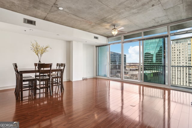 dining space with ceiling fan, dark hardwood / wood-style floors, and a wall of windows