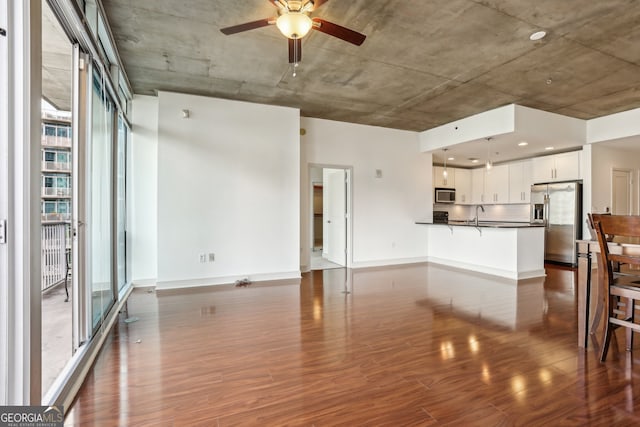 unfurnished living room with dark hardwood / wood-style flooring, sink, and ceiling fan