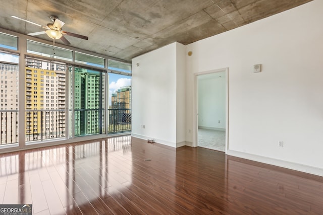 unfurnished room with dark wood-type flooring, expansive windows, and ceiling fan