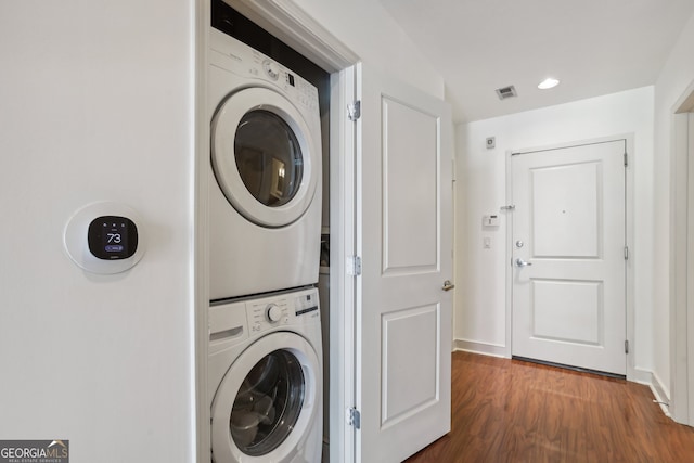 laundry room featuring dark hardwood / wood-style flooring and stacked washing maching and dryer