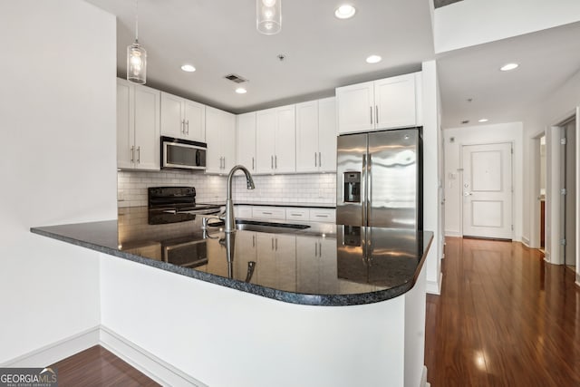 kitchen with kitchen peninsula, appliances with stainless steel finishes, hanging light fixtures, and sink