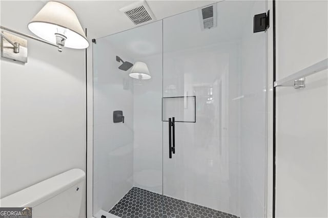 bathroom featuring a shower with shower door and toilet