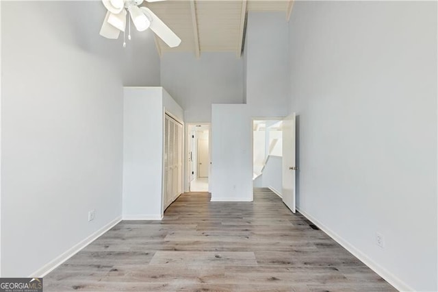 spare room with a high ceiling, light hardwood / wood-style flooring, and ceiling fan