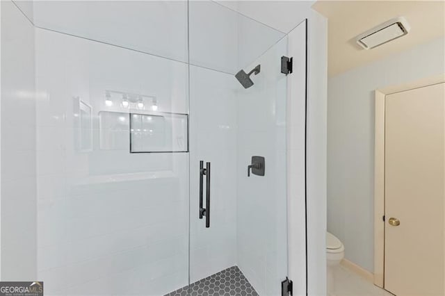 bathroom featuring toilet and a shower with shower door