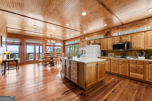 kitchen with hardwood / wood-style floors, white fridge, a kitchen island with sink, and french doors