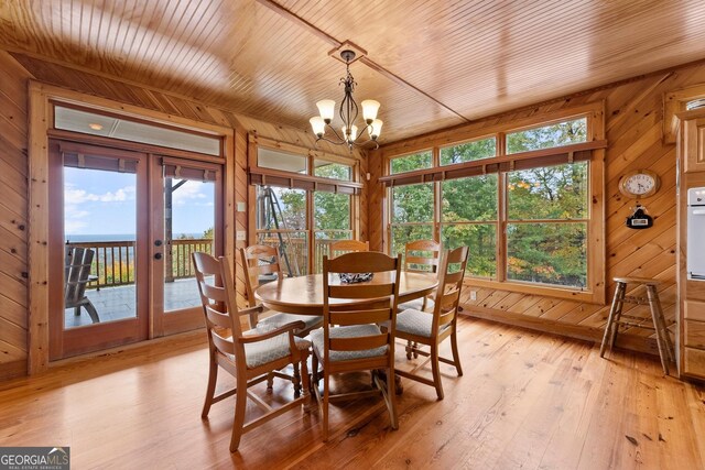 dining area featuring french doors, light hardwood / wood-style floors, and wood walls