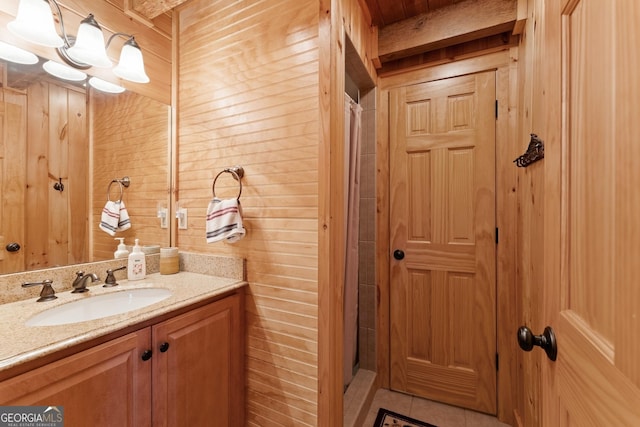 bathroom featuring vanity, wooden walls, tile patterned floors, and a shower with shower curtain