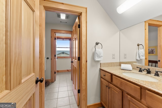 bathroom with tile patterned flooring, vanity, and vaulted ceiling