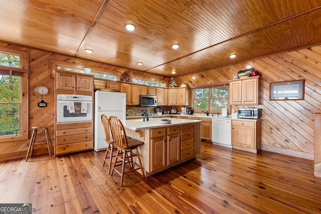 kitchen featuring a kitchen island with sink, hardwood / wood-style floors, wooden ceiling, and white appliances