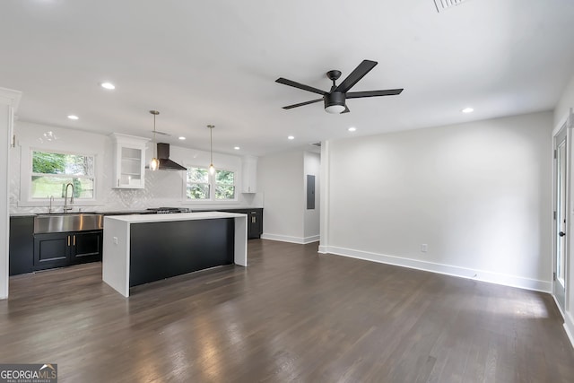 kitchen with wall chimney exhaust hood, sink, a kitchen island, and plenty of natural light