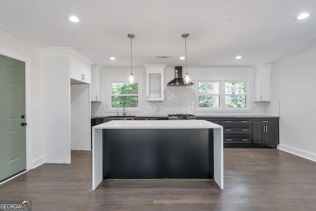 kitchen featuring white cabinets, a wealth of natural light, wall chimney exhaust hood, and hanging light fixtures