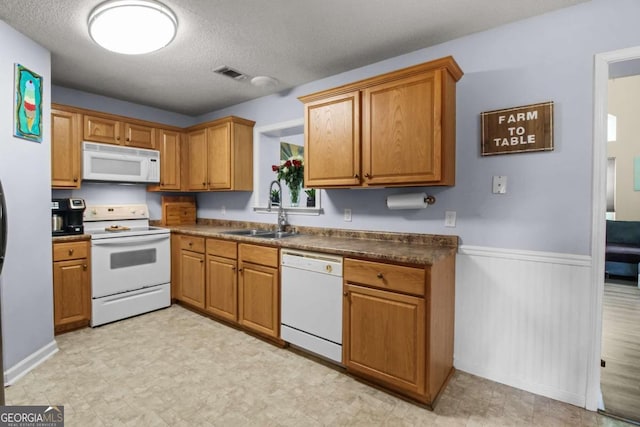 kitchen featuring a textured ceiling, sink, and white appliances