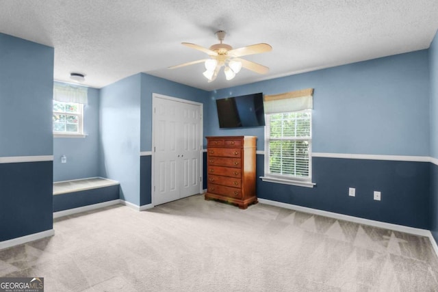 carpeted bedroom with a closet, ceiling fan, and a textured ceiling