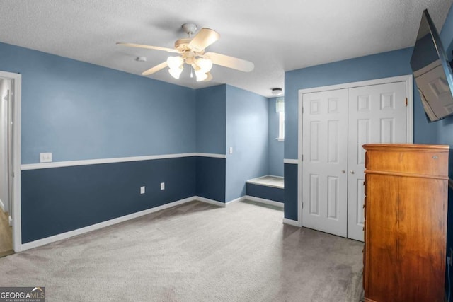 unfurnished bedroom featuring a closet, ceiling fan, light carpet, and a textured ceiling