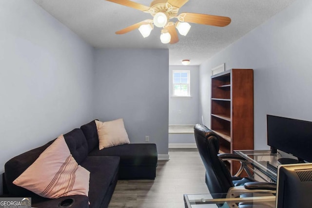 home office with a textured ceiling, light wood-type flooring, and ceiling fan