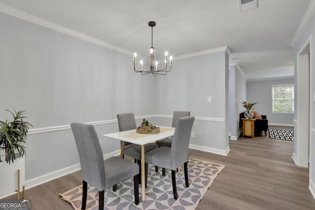 dining space with wood-type flooring, ornamental molding, and an inviting chandelier