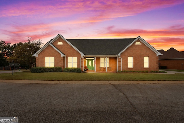 single story home with brick siding and a lawn