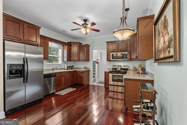 kitchen with appliances with stainless steel finishes, ceiling fan, crown molding, dark wood-type flooring, and pendant lighting