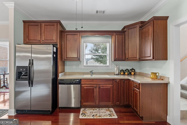 kitchen featuring a sink, visible vents, light countertops, appliances with stainless steel finishes, and dark wood finished floors