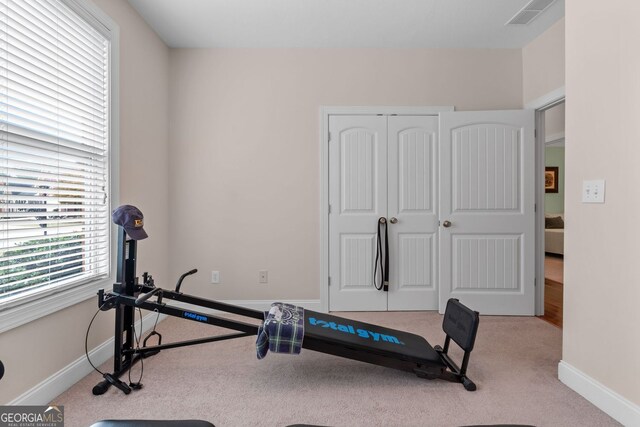 workout room featuring light carpet