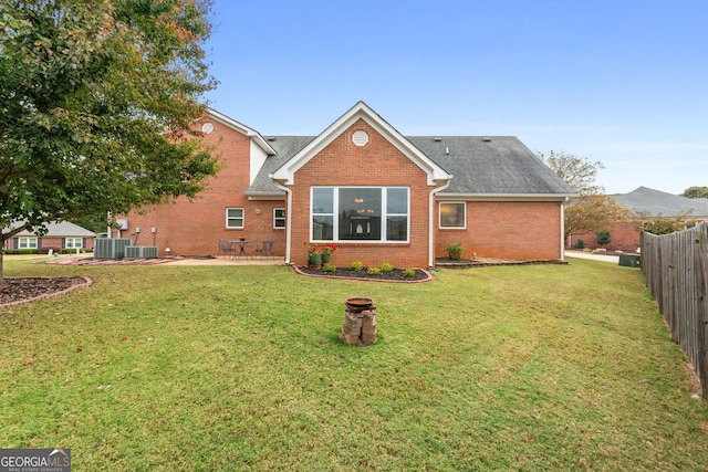 rear view of property featuring a patio, central AC, brick siding, fence, and a yard