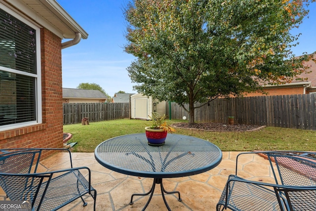 view of patio with an outbuilding, a fenced backyard, and a shed