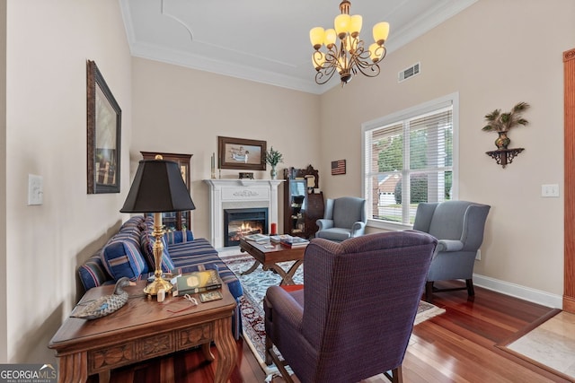 living area with a lit fireplace, baseboards, crown molding, and wood finished floors