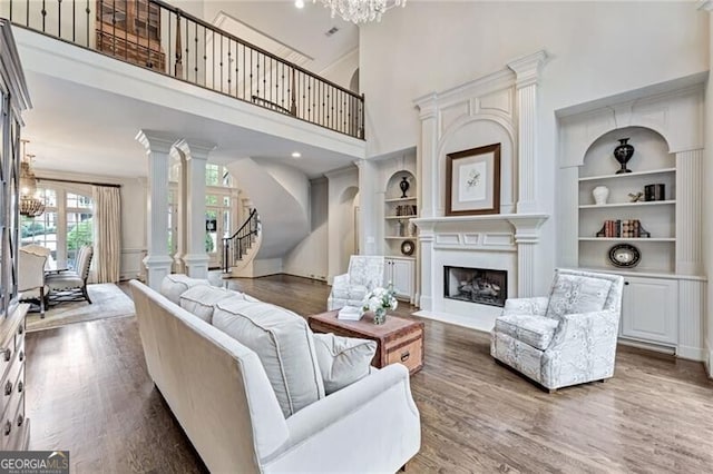 living room featuring a towering ceiling, built in features, dark hardwood / wood-style floors, and a chandelier