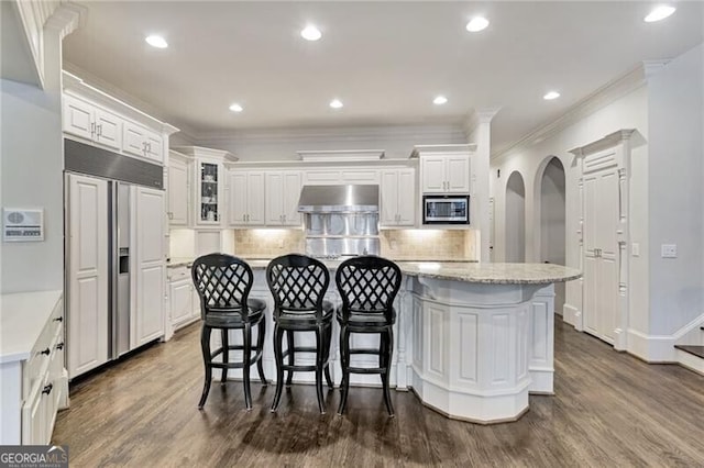 kitchen with dark hardwood / wood-style floors, white cabinetry, built in appliances, and a center island