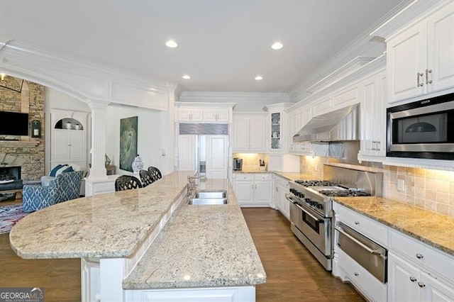 kitchen with built in appliances, white cabinetry, extractor fan, and a spacious island