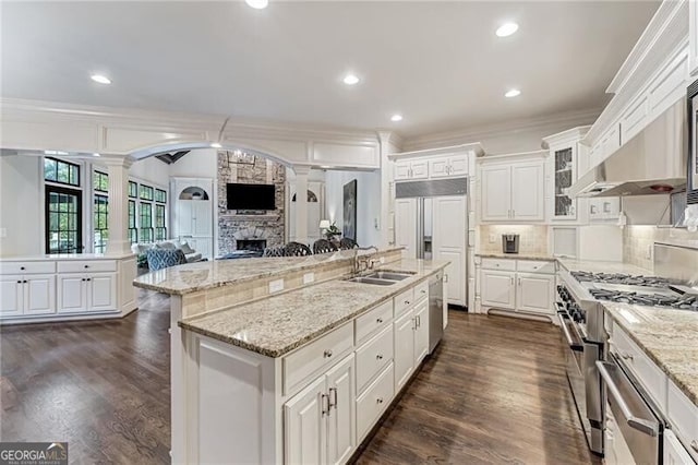 kitchen with high quality appliances, a kitchen island with sink, white cabinetry, and ornamental molding