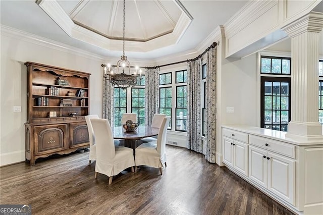 dining space featuring crown molding, an inviting chandelier, dark wood-type flooring, decorative columns, and a tray ceiling