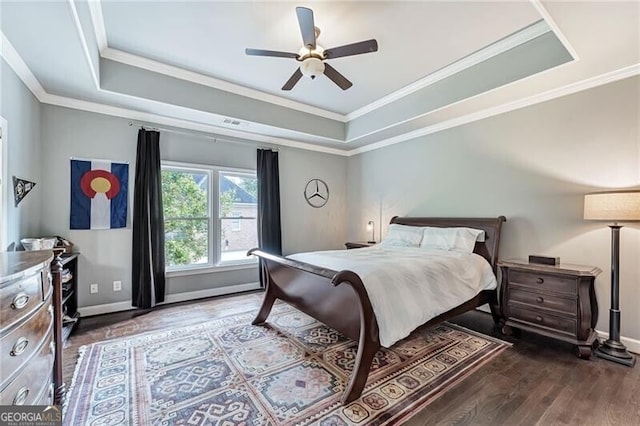 bedroom with ornamental molding, dark hardwood / wood-style flooring, ceiling fan, and a raised ceiling