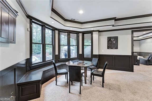 dining room with ornamental molding, light carpet, and a tray ceiling