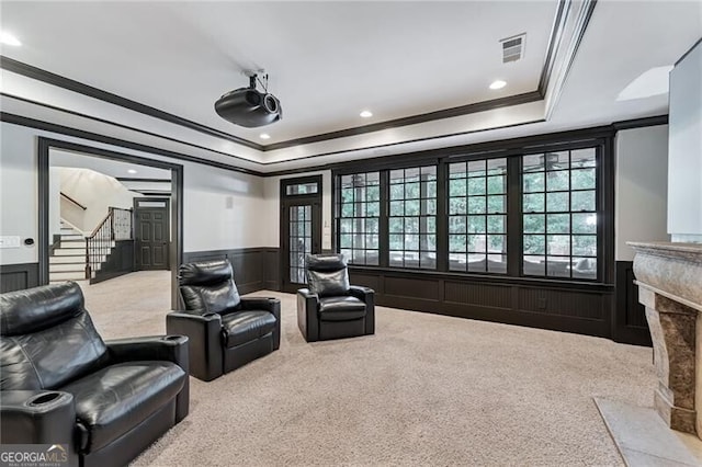 carpeted cinema room featuring ornamental molding and a raised ceiling