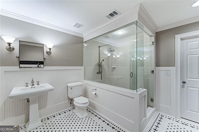 bathroom with toilet, crown molding, and a shower with shower door