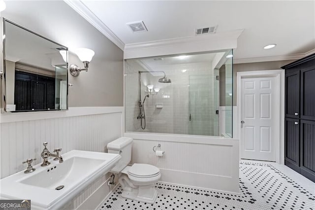 bathroom with tile patterned flooring, sink, a tile shower, crown molding, and toilet