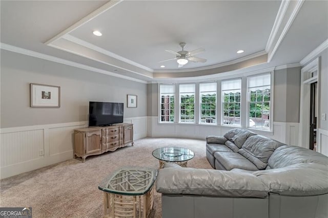 living room with carpet floors, ceiling fan, crown molding, and a tray ceiling